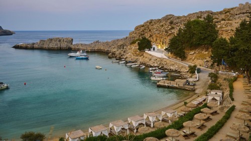 Bay with sun loungers and clear water, St Paul's Chapel, Paul's Bay, below the Acropolis of Lindos,