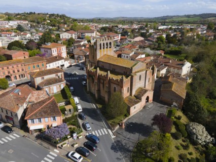 View of a town with a central church tower and surrounding houses on a sunny day, Eglise