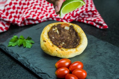 Delicious Lebanese (Arabic) food, squeezing lemon into legitimate sfihas on a black granite