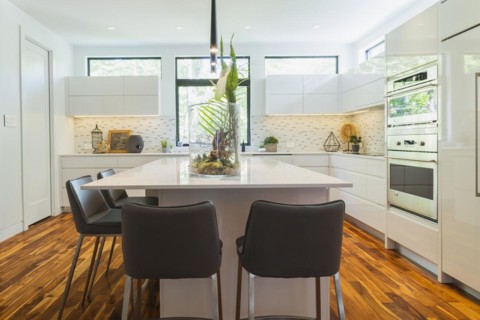 White high-gloss lacquered cabinets and island with grey leather bar stools and white quartz