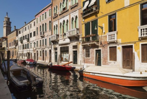 Narrow canal with moored boats and Renaissance architectural style residential palace buildings,