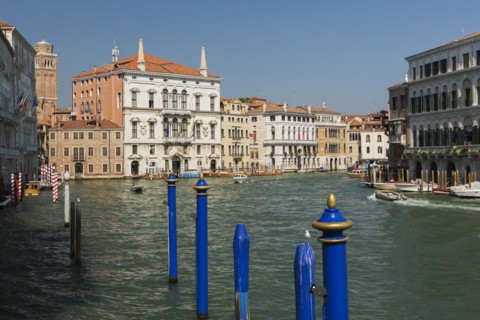 Blue mooring posts and water taxis on Grand canal with Renaissance architectural style residential