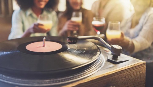 Friends enjoy drinks vinyl record playing together in cozy setting at sunset, bokeh effect ai