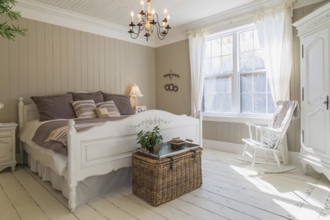 King size bed with light brown and beige striped bedspread, white painted wooden headboard and