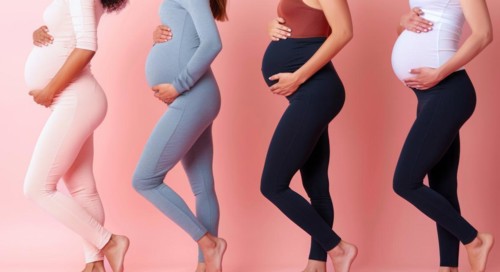 A group of pregnant women are standing in a line, with each woman wearing a different colored