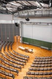 View from above into an empty lecture theatre with rows of seats and lectern, interior photo,