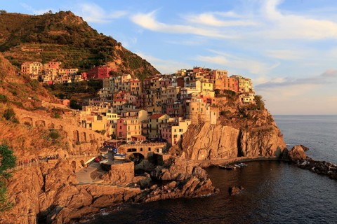 Morning sun shines on a colourful coastal town on the Italian Riviera with a view of the calm sea,