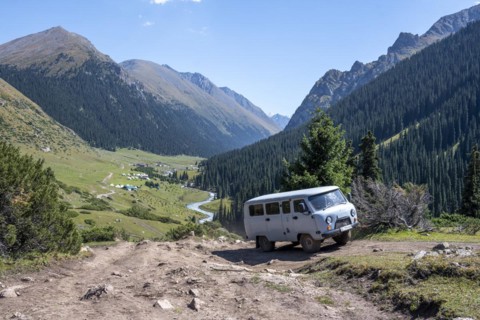 UAZ Buchanka, Russian off-road vehicle on 4x4 track, green mountain valley with village Altyn
