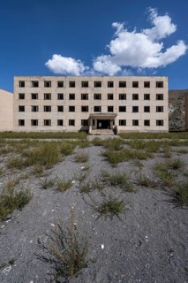 Abandoned destroyed residential building, old Soviet block of flats in the ghost town, Engilchek,