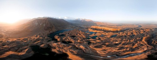 Atmospheric aerial view, high mountain landscape with glacier moraines and mountain lakes, behind