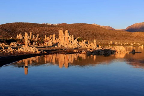 Warm sunset light on tufa towers at Mono Lake with calm water reflection, Mono Lake, North America,