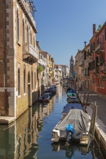 Moored boats on San Barnaba canal with footbridge and old architectural style residential buildings