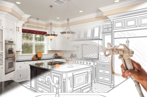 Professional spray painter holding spray gun spraying renovated kitchen over design drawing