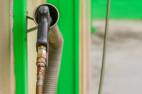 Rear view of black handle of car wash high pressure water gun with long nozzle inserted into metal