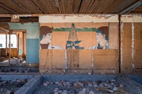 Destroyed abandoned classroom of the old school, wall painting with Soviet miners, ghost town,