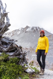 Young woman in yellow jacket standing in front of a volcano, Chaiten Volcano, Carretara Austral,