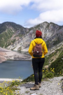 Young woman in yellow jacket standing in front of a volcano, Chaiten Volcano, Carretara Austral,