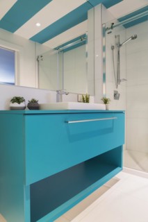 Blue laminated vanity with white rectangular shaped sink, clear glass shower stall in guest