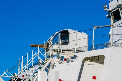 Closeup of gun and covered seat for gunner with covered barrel on a military style frigate in