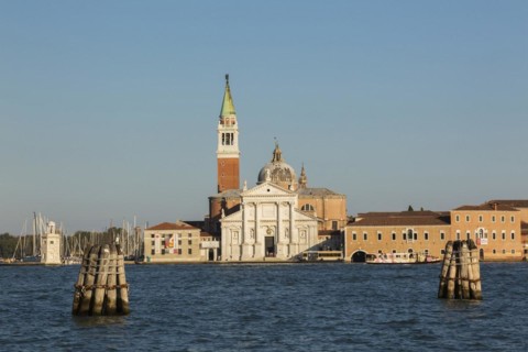 Canal lane markers in Venetian lagoon and 16th century Benedictine church of San Giorgio Maggiore