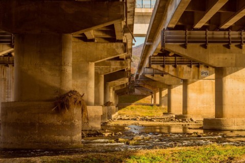Underside view of columns of two highway overpass next to each other over river in South Korea