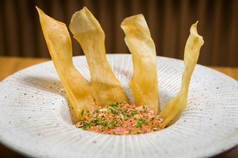 PERUVIAN FOOD. Spiced Salmon Ceviche with Chives and Lime on a white plate served with Fried Sweet