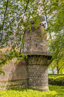 Historic windmill, part of an old city wall, behind trees in the sunshine, historic fortress Zons,