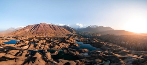 Atmospheric aerial view, high mountain landscape with glacier moraines and mountain lakes, behind