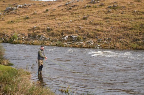 Fisherman fly fishing rainbow trout on mountain in beautiful scenery