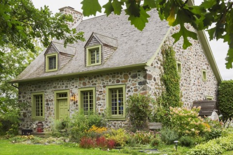 Old circa 1735 Canadiana fieldstone house facade with lime green trim and cedar wood shingles roof