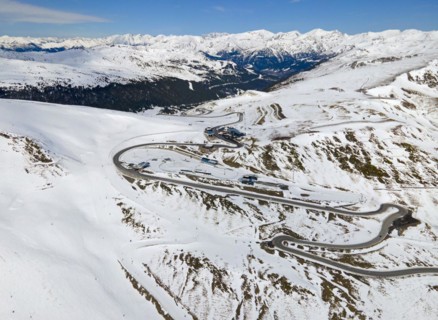 Mountain road winds through a wintry landscape in daylight, serpentine road near El Pas de la Casa,
