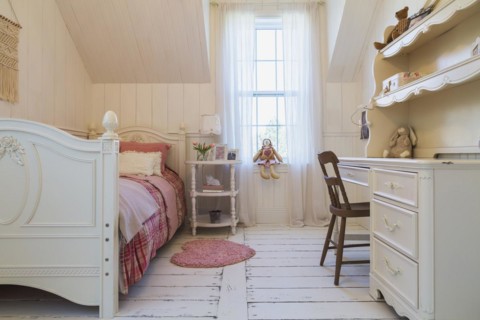 Single bed with red, pink and grey tartan bedspread, white painted antique style wooden headboard
