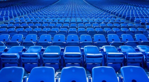 Big empty stadium full of blue seats, AI generated