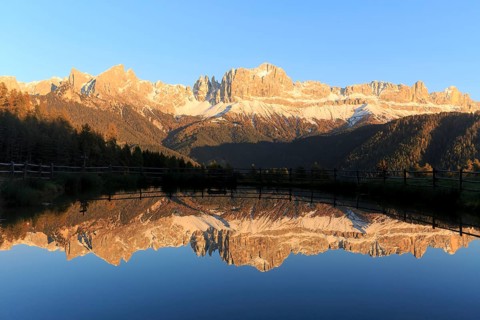 Sunrise behind the mountains with bright red colours reflected in the clear water of the lake,