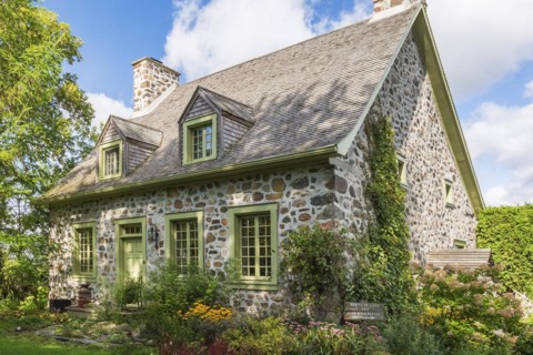 Old circa 1735 Canadiana fieldstone house facade with lime green trim and cedar wood shingles roof