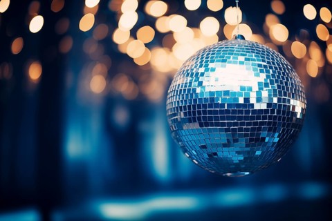 A disco ball is suspended from the ceiling at party in nightclub, reflecting the lights and
