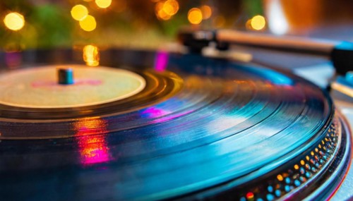 Close-up of a turntable with a vinyl record illuminated by blue light and soft bokeh in the