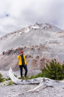 Young woman in yellow jacket standing in front of a volcano, Chaiten Volcano, Carretara Austral,