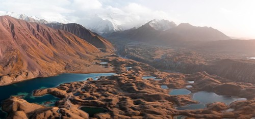 Atmospheric aerial view, high mountain landscape with glacier moraines and mountain lakes, behind