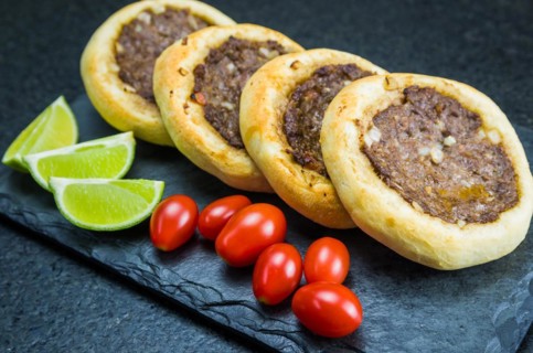 Delicious Lebanese (Arabic) food, genuine sfihas on a slate plate with tomatoes and lemons