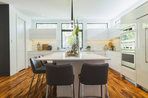 White high-gloss lacquered cabinets and island with grey leather bar stools and white quartz
