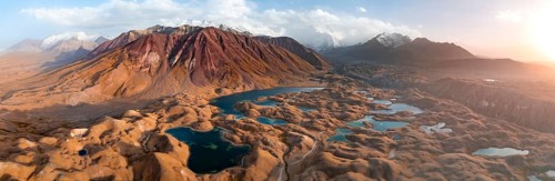 Atmospheric aerial view, high mountain landscape with glacier moraines and mountain lakes, behind