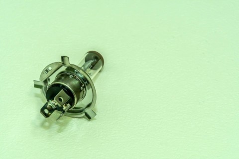 Automobile halogen headlamp bulb isolated on textured background