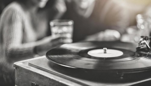 Friends enjoy drinks vinyl record playing together in cozy setting at sunset, bokeh effect ai