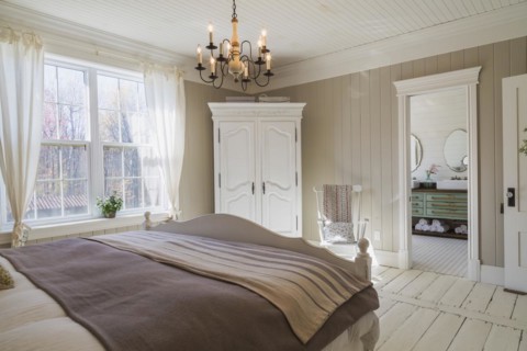 King size bed with light brown and beige striped bedspread, white painted wooden headboard and