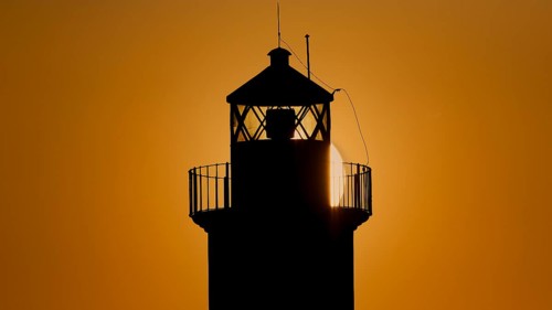 A lighthouse in silhouette with a dazzling sunrise in the background, sunrise, dawn, Fort of Saint