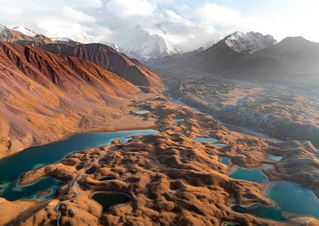 Atmospheric aerial view, high mountain landscape with glacier moraines and mountain lakes, behind