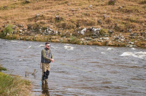 Fisherman fly fishing rainbow trout on mountain in beautiful scenery