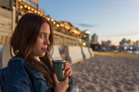 Young girl drinking mate tea tea (chimarrao) on the beach