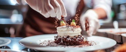 Chef is decorating a dessert with berries and other delicious additions of sweets and whipped